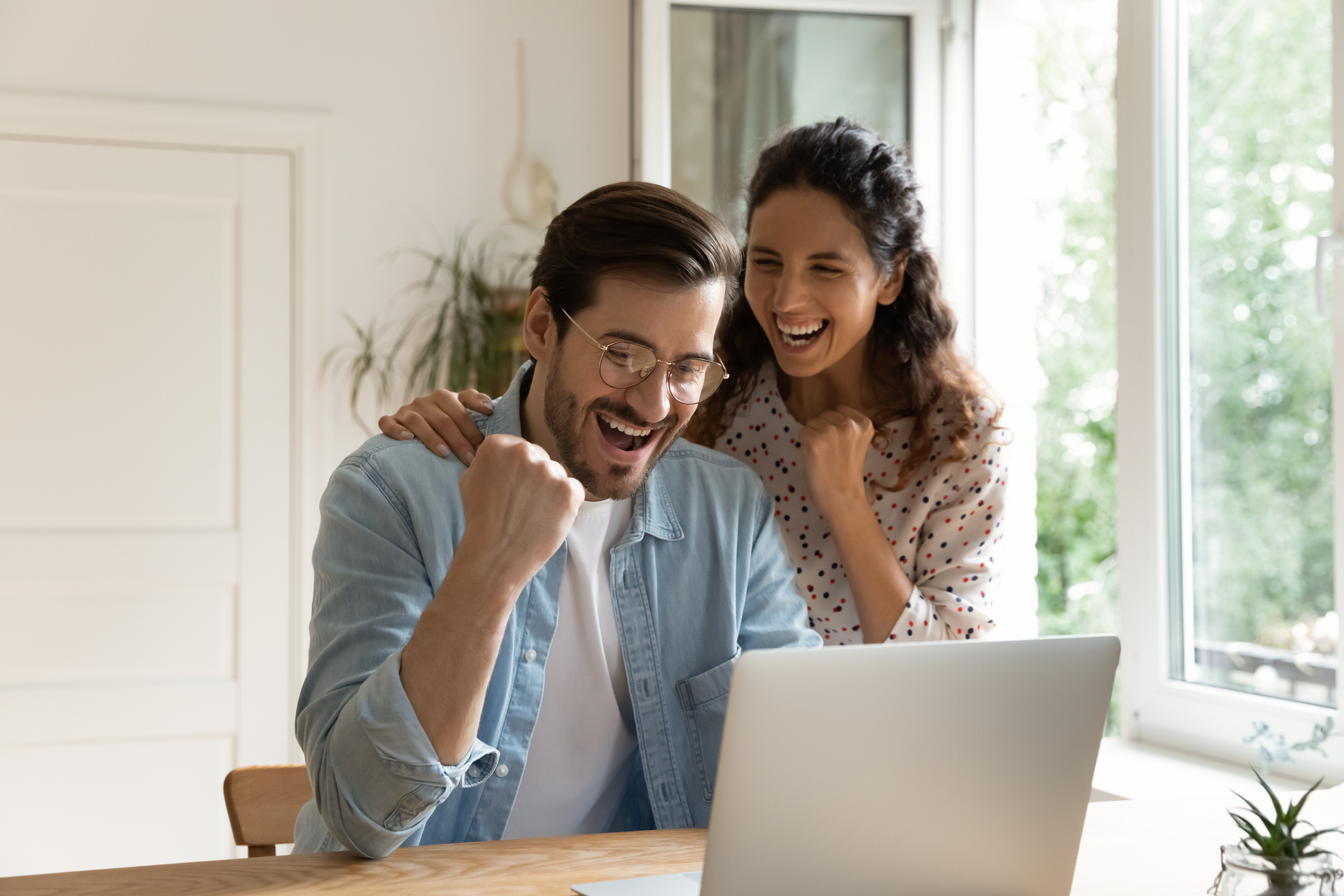 Excited couple cheering by computer- Tips for getting out of debt