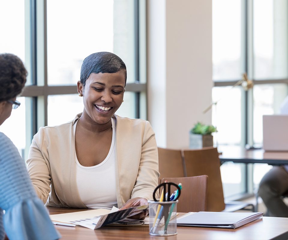 Smiling woman reviews paperwork while conducting a job interview