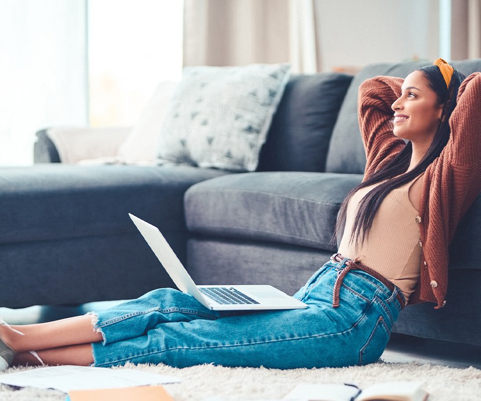 Woman leaning back to relax on couch with an open laptop computer