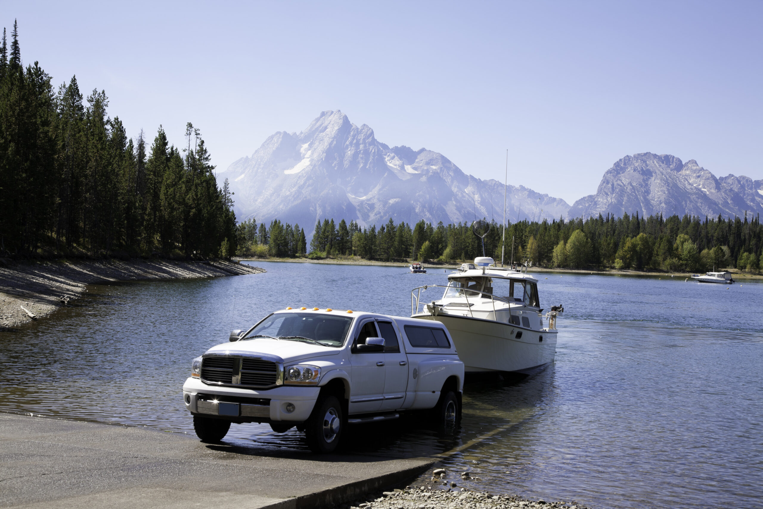 Vehicle driving up boat ramp while towing boat out of lake