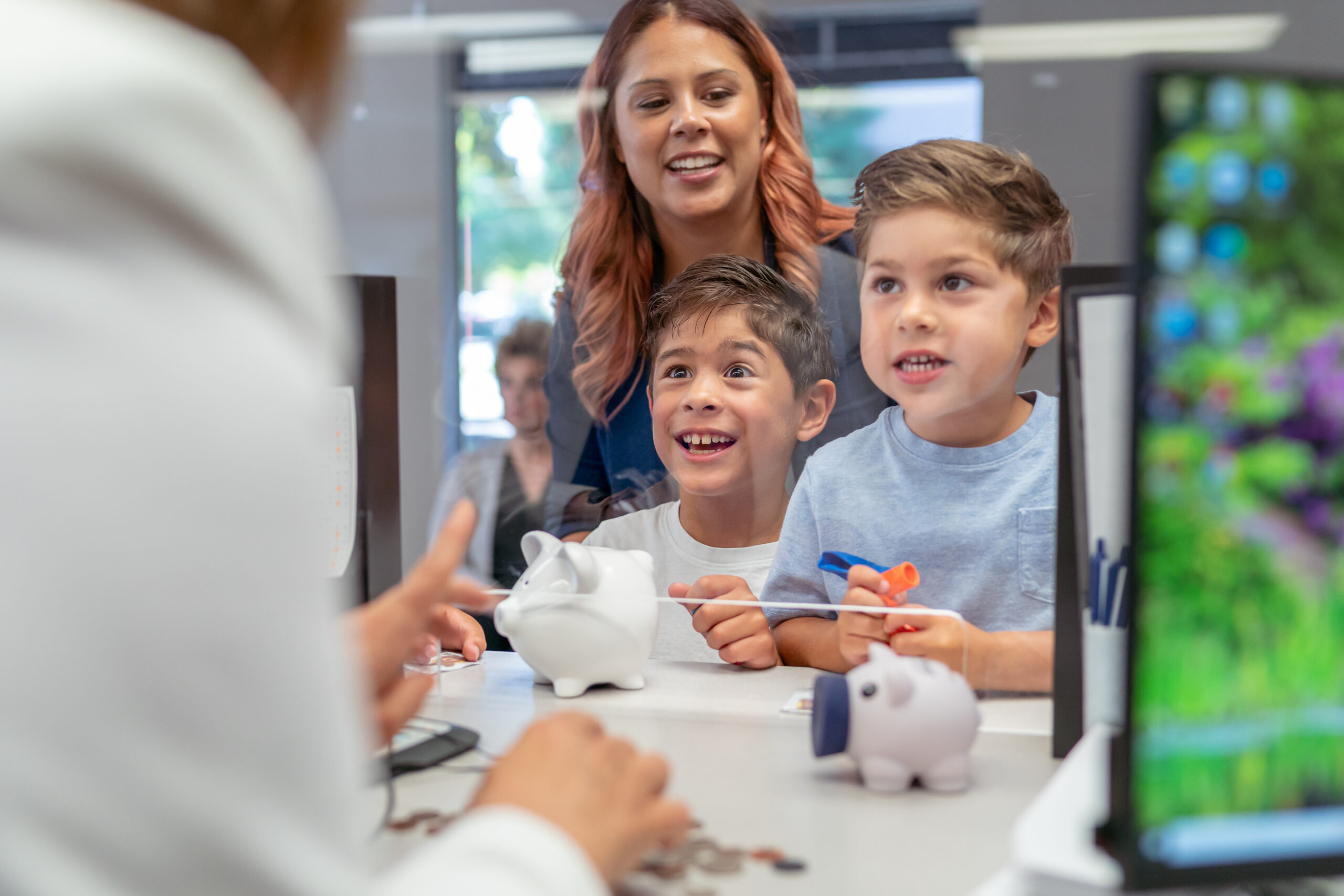 Mom teaching her sons good money habits and opening a savings account at a credit union