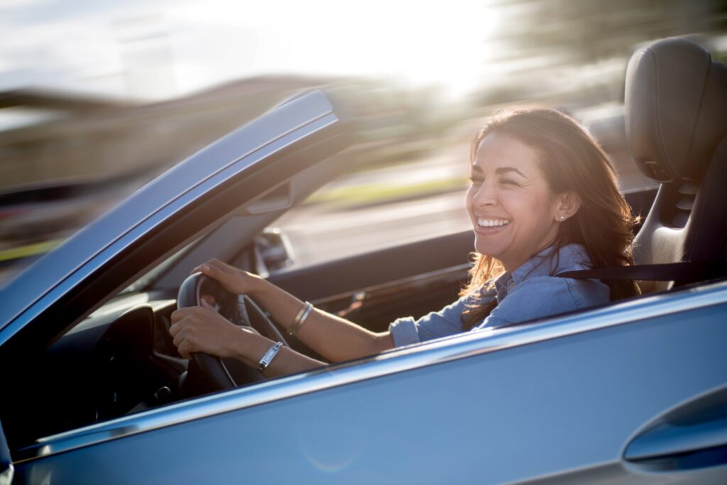 Woman driving a blue convertible car and having a lot of fun